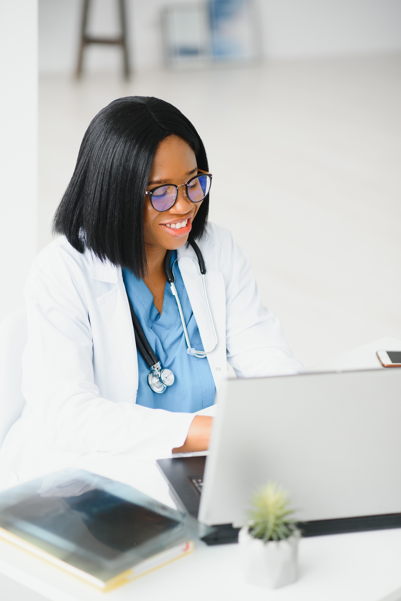 Young African-American doctor working on laptop in clinic.